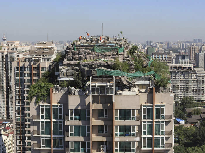 Seen here, workers demolish a privately-built villa, surrounded by imitation rocks, on the rooftop of a 26-story residential building in Beijing in August of 2013. The elaborate villa, complete with a garden, was built illegally on top of a Beijing apartment block and took 15 days to demolish.