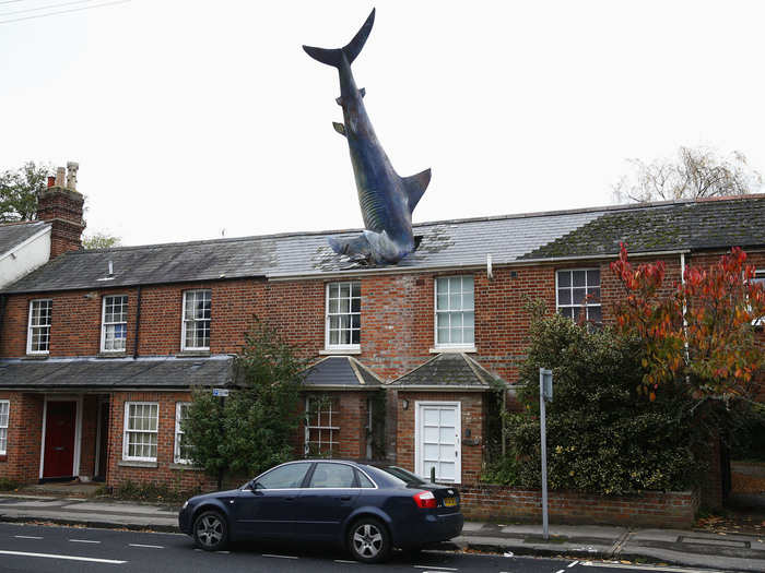 In "Sharknado"-like fashion, a 25-foot-long model shark made of fiberglass, appears to be plummeting into this house in Oxford, England. It was erected on the 41st anniversary of the dropping of the atomic bomb on Nagasaki.