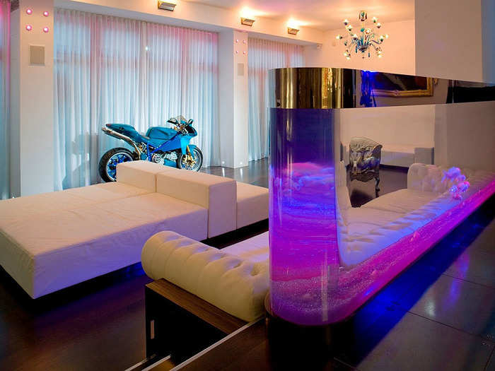 The white couches, pink aquarium, and motorcycle really scream 