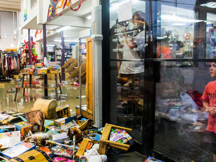 Austinite Lucas Rivas looks into the flooded Whole Earth Provisions Company on Lamar Street.