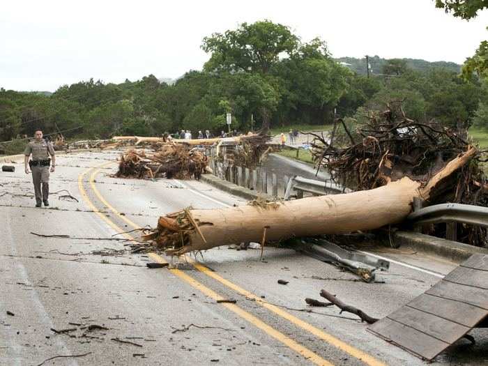 Department of Public Safety Trooper Marcus Gonzales walked on the Highway 12 bridge over the Blanco River which was blocked by large trees.