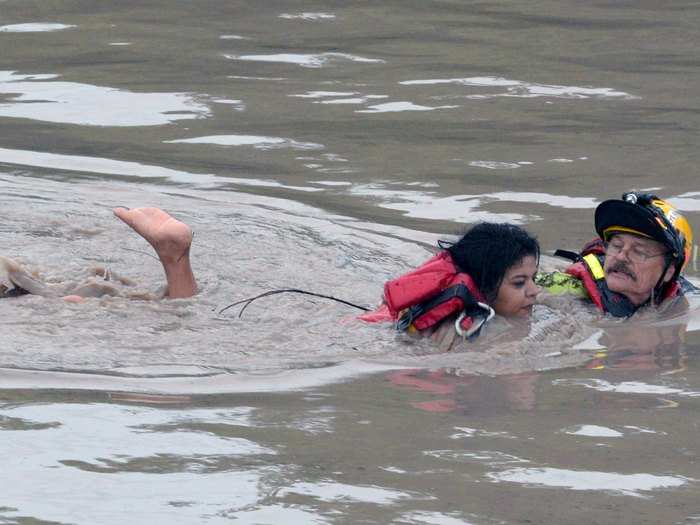 Similarly, San Marcos Firefighter Jay Horton is seen here rescuing a woman from flood waters in San Marcos, Texas on Sunday.