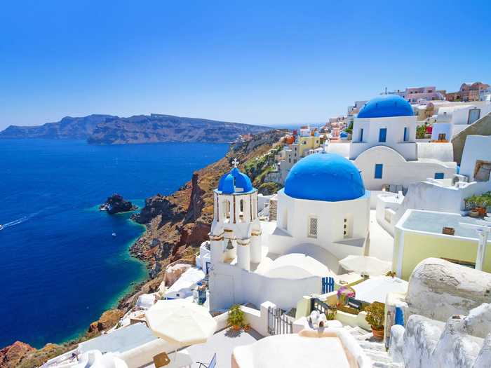 The Greek island of Santorini sits on the Aegean sea and is easily recognizable from its architecture: a cluster of white stone buildings topped with rich blue roofs that sit on cliffs above the sea.