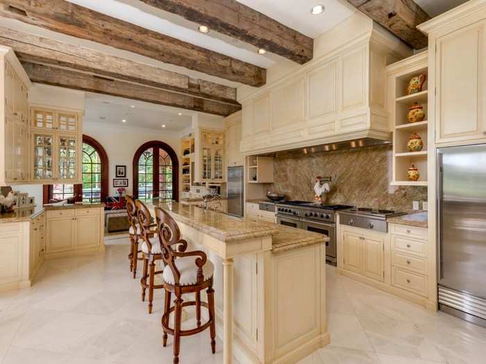 The kitchen has a breakfast counter, a double stove, and exposed beam ceilings.