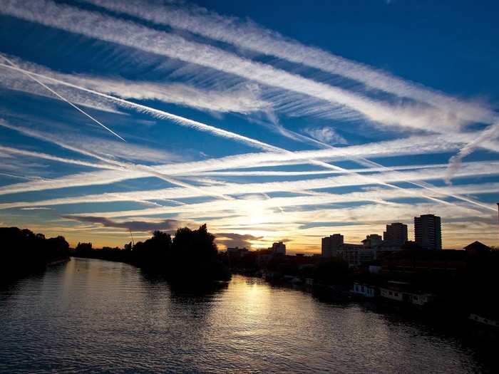 Globalized transportation networks, especially commercial aviation, are a major contributor of air pollution and greenhouse gas emissions, like the chem-trails seen here in the west London sky over the River Thames.