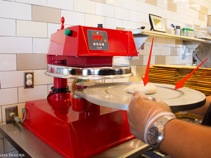 For my first pizza, I opted to build my own. Chef Brad took a slab of dough and placed it on this machine, which flattens and shapes its crust in the metal plate