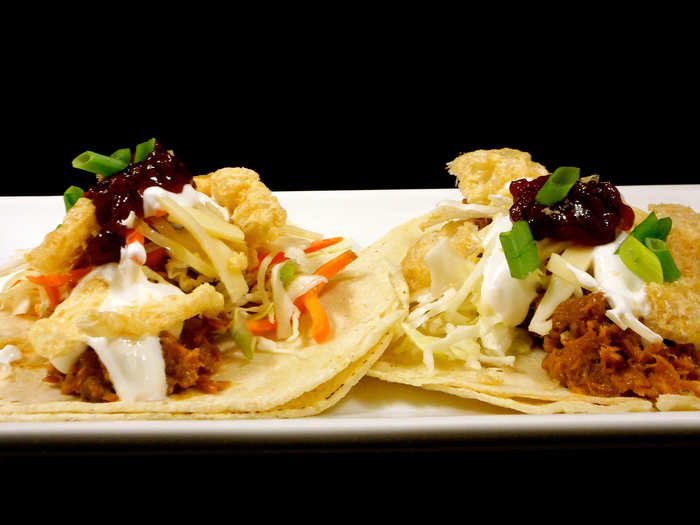 Oslo Taco: Seared braised, peppercorn-rubbed pork, layered with Norwegian Jarlsburg cheese, pickled cabbage slaw, red onion, apple-smoked bacon and lingonberry relish sour cream, topped with pork cracklins and served on two flour tortillas.