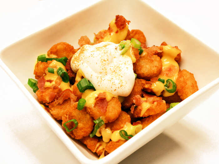 Totchos Tater tots smothered in cheddar cheese sauce with seasoned sour cream, bacon bits and green onions (chicken or taco-style beef optional). Gluten-free.