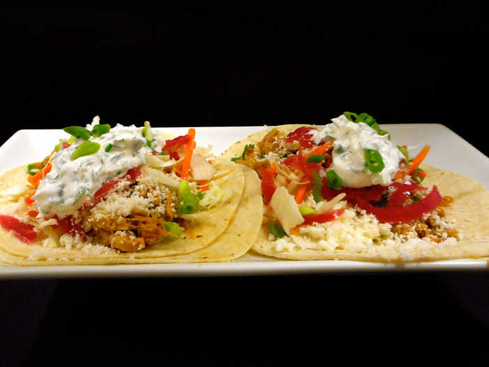 Yucatan Taco: Seasoned chicken chorizo braised in tequila and red wine vinegar served with green cabbage carrot slaw, queso fresco, pickled red onion and cilantro sour cream on two flour tortillas.