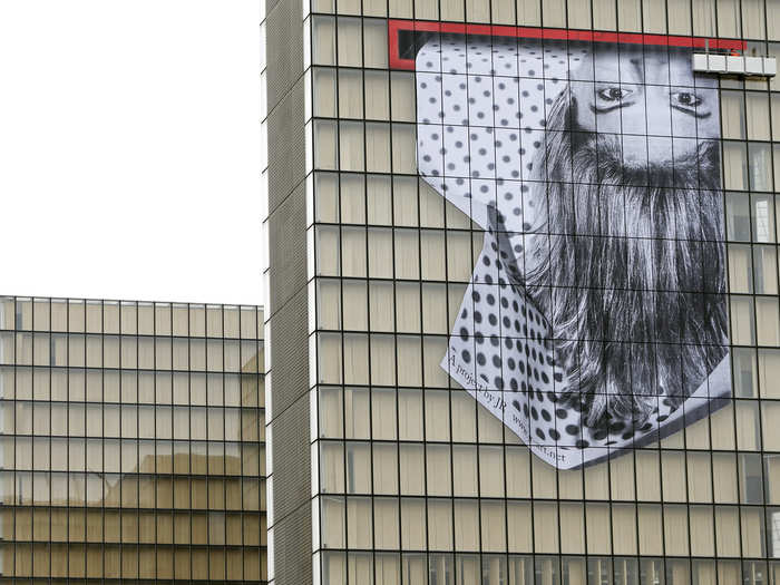 For another exhibit, JR created an upside-down portrait of paper strips. It covered the facade of the French National Library in Paris in November 2013.