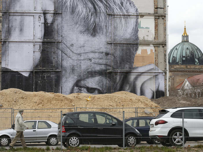 A man walks beside another creation by JR near the Berlin cathedral.