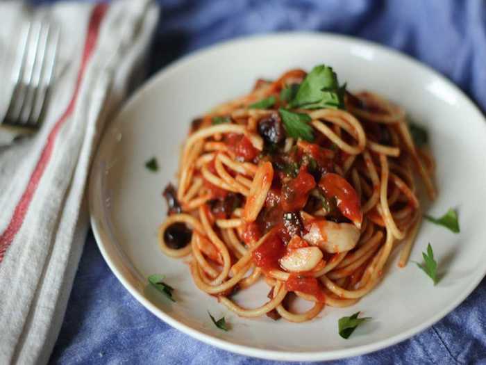 Because of its many ingredients, spaghetti alla puttanesca translates to something along the lines of "spaghetti in the garbage style." The dish comes from the southern region of Campania and includes olives, capers, tomatoes, olive oil, and anchovies.