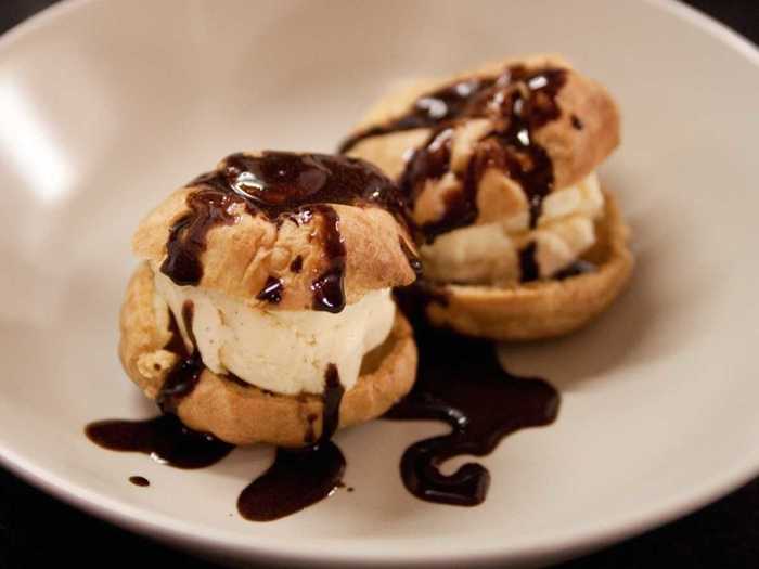 Profiteroles are little puff pastries filled with vanilla ice cream and topped with velvety chocolate sauce.