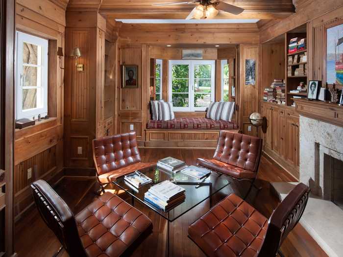 The study is cozy with wood walls and a fireplace.