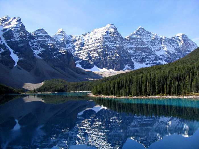 See the Rocky Mountains reflect in the crystal-clear waters of Moraine Lake at Banff National Park in Canada.