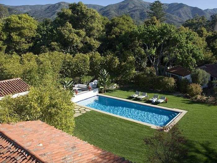 The estate has a large backyard area with a swimming pool, tennis court, and lots of Spanish-inspired decor.