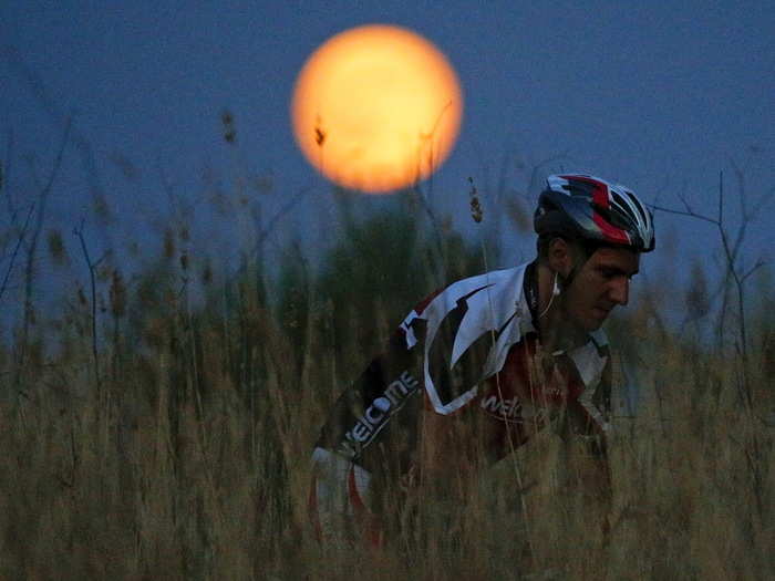 A cyclist rides under moonlight in Rome, Italy.