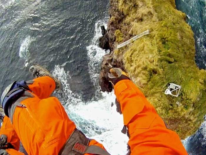 Another key job of the Coast Guard is to maintain navigation service aids throughout the waters around Alaska. Here, an electronics technician is lowered to a communication and navigation station on an island in Cold Bay.