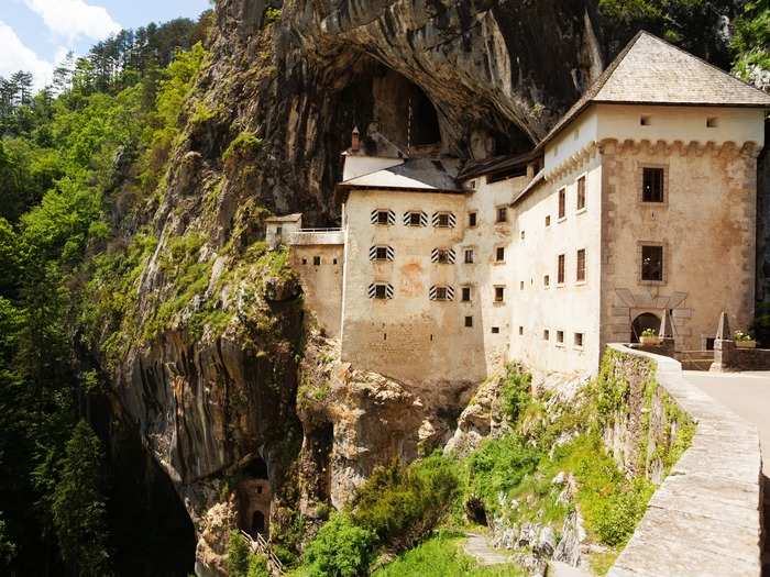 LARGEST CAVE CASTLE: The Predjama Castle, located near Postojna, Slovenia, resides in the entrance of a cave system that is located halfway up a 400-foot cliff face. The castle was originally built in the 13th century and is a beloved attraction for visitors of the country.