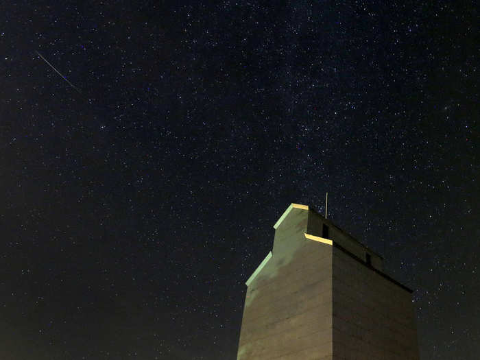 A meteor streaks across the sky behind a grain elevator in Iowa.