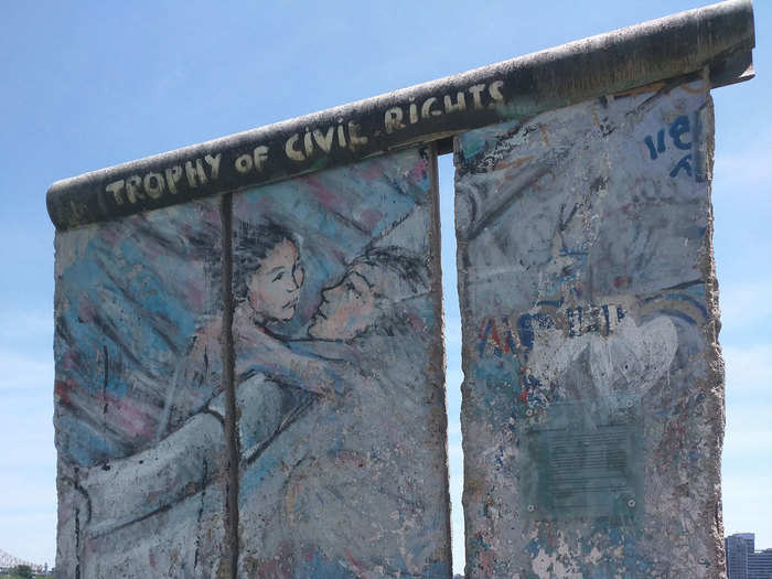 Three segments of the Berlin Wall were gifted to the United Nations Headquarters in New York City by the Federal Republic of Germany. The illustration displays a boy and a girl meeting over the wall.