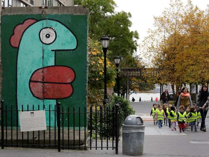 In this photo, schoolchildren can be seen walking near a piece of the Berlin Wall that sits on display in Battery Park in New York City.