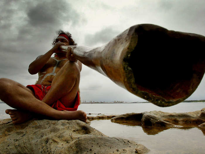 Aboriginal performer Les Saxby plays a traditional "didgeridoo" instrument on the shores of Sydney