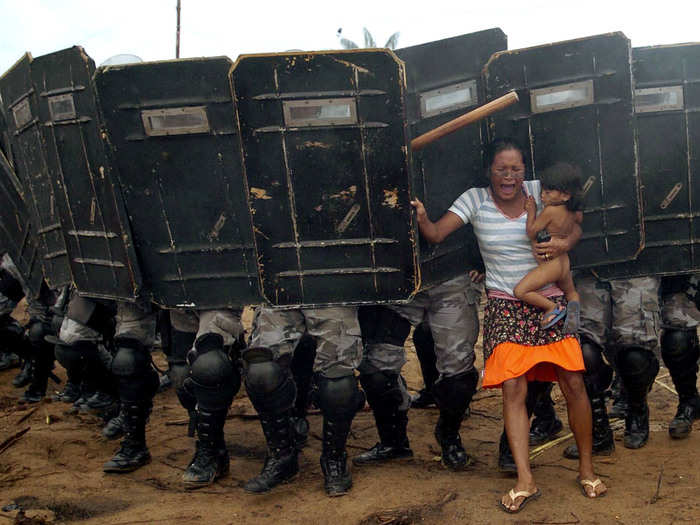 Shot in 2008, this photo shows a woman and her frightened child trying to resist the advance of Amazonas state policemen. They were two of some 200 natives being pushed off their land — a privately-owned tract in the hear of the Brazilian Amazon — that day.