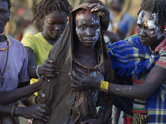 A Pokot girl, covered in animal skins, walks to a place where she will rest after being circumcised in a tribal ritual in a village about 80 kilometers from the town of Marigat, Kenya. The traditional practice of circumcision within the Pokot tribe is a rite of passage that marks the transition to womanhood and is a requirement for all girls before they marry.