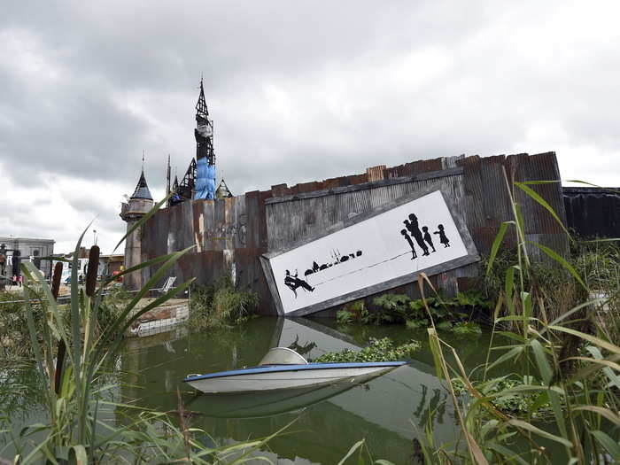 A mural decrying economic inequality hangs precariously above an overgrown lagoon.