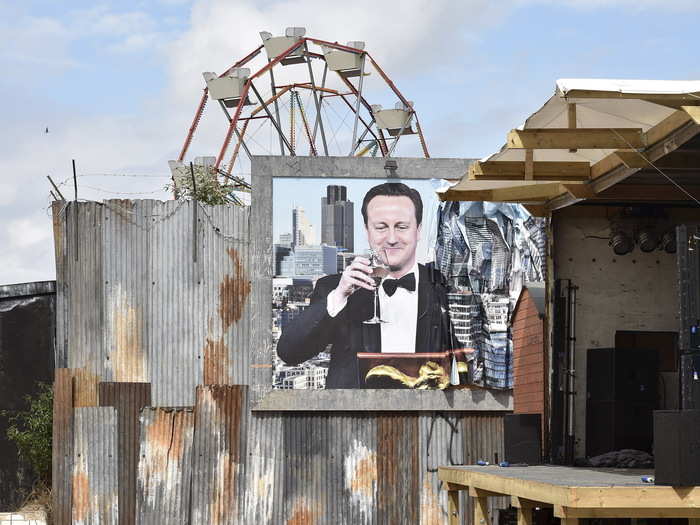 This smiling portrait of British Prime Minister David Cameron looks down from a damaged billboard next to an outdoor film screening.