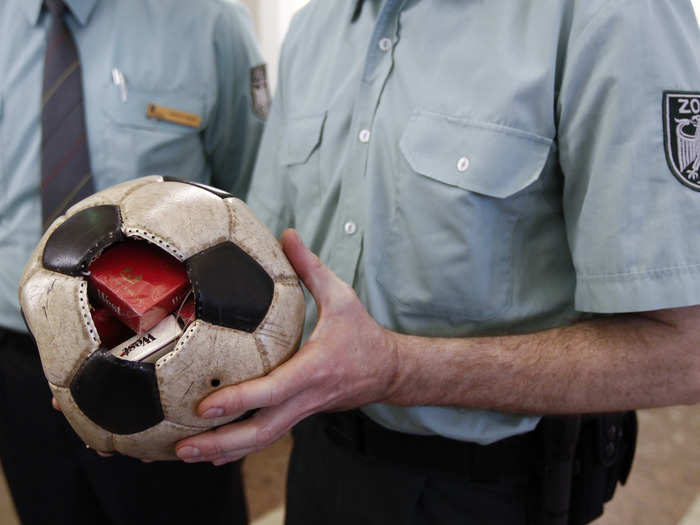 In this photo, a German customs officer holds a confiscated soccer ball filled with cigarettes.