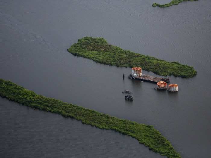 Rusted-over oil tanks on the Mississippi river delta float by, serving as a permanent reminder of the most costly hurricane in American history. The government estimates that 8 million gallons of oil was spilled and rendered useless from holding tanks like these during the storm.