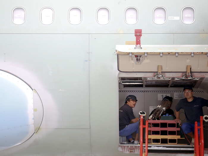 Workers have to crouch inside the eventual baggage hold to install everything from insulation, to electronics and communications equipment.