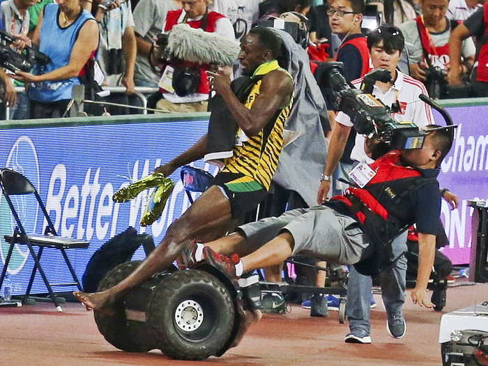 Usain Bolt of Jamaica is hit by a cameraman on a Segway as he celebrates after winning the men