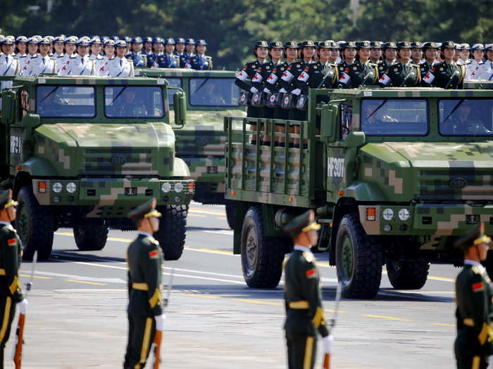 During the parade, military trucks rode by carrying both male and female units.