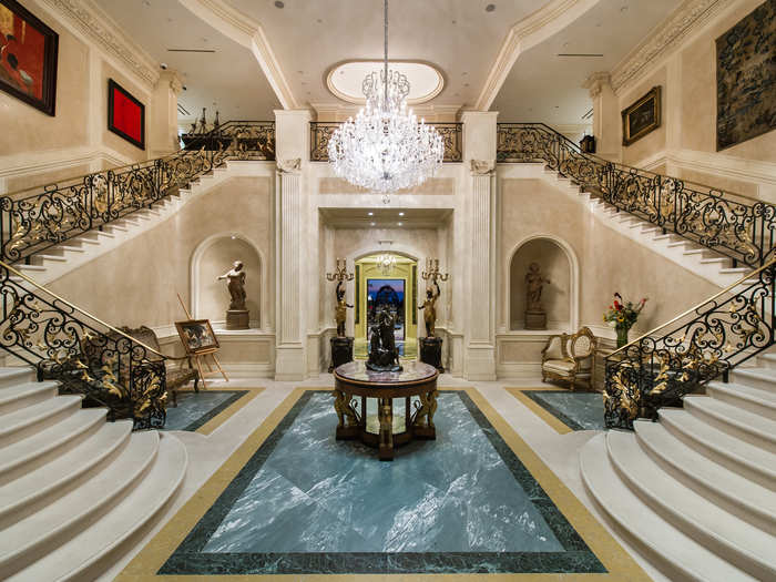 Visitors pass through three sets of gates before arriving at the grand home. The two-story entry has a pair of curved marble staircases.