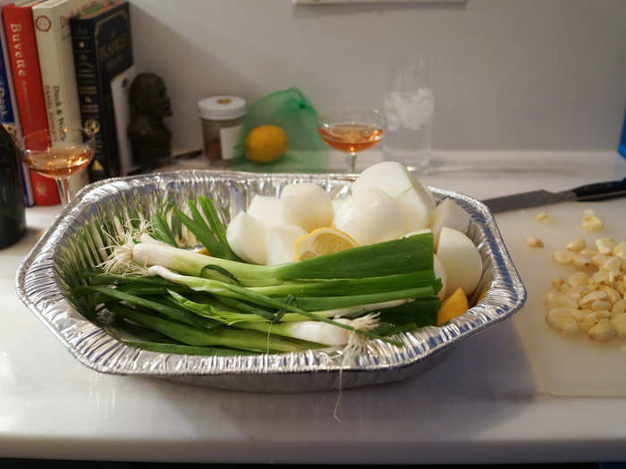 We carried our glasses into the kitchen and did our mise en place. I halved six lemons, quartered four white onions, chopped one cup garlic, and rinsed two bunches green onion.