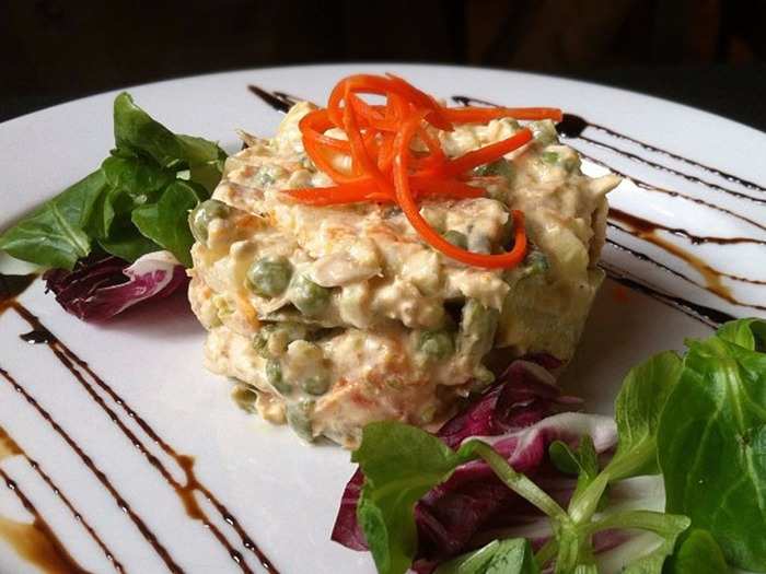 Ensaladilla Rusa — potato salad mixed with tuna, mayonnaise, and vegetables like carrots and peas — may have its roots in Russia, but the dish is popular across eateries in Spain.