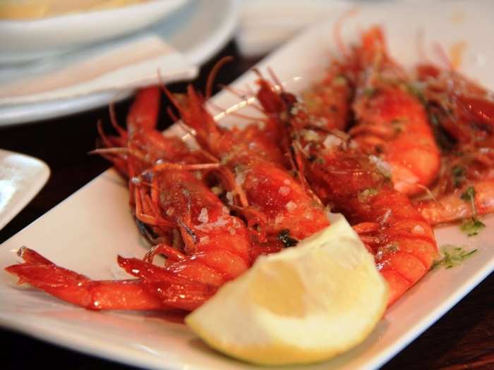 Gambas a la plancha are whole, unpeeled shrimps that are salted and cooked on a flat iron grill. The heads are left on for extra flavor.