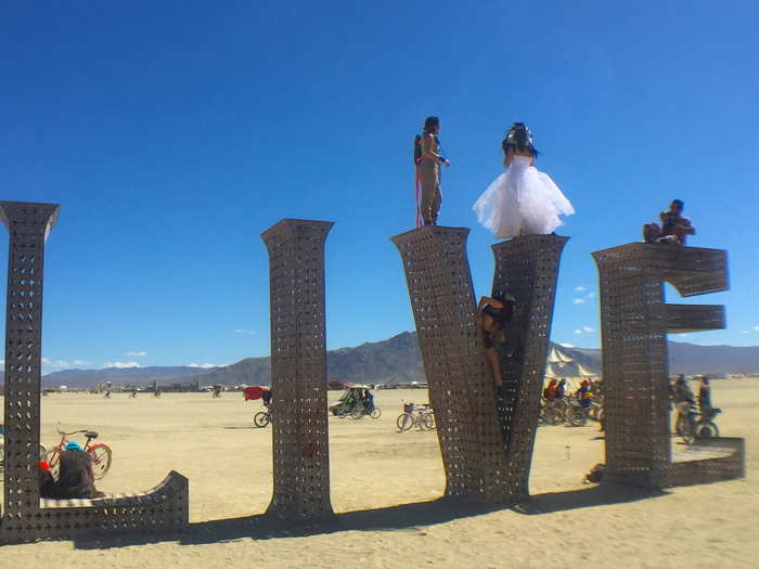 People climb all over giant art installations randomly placed throughout the desert.