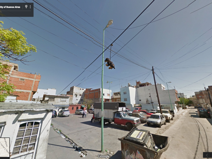 For some unknown reason, a stuffed animal dog is hanging from its leash off a telephone wire in Buenos Aires. It