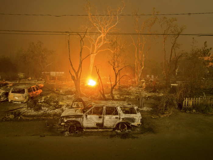 A section of the Valley Fire in the background illuminates its path of destruction through a neighborhood of homes and vehicles.