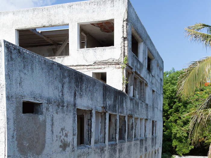 A large unfinished building sits off to the side of the mansion.