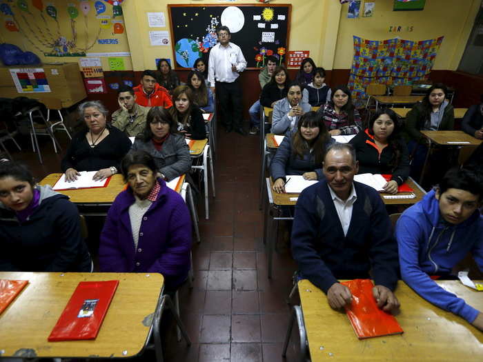 Not all students are children. Guillermo Valenzuela teaches primary grade students at  a night program for adults called Laura Vicuna School, in a busy neighborhood of Santiago, Chile.