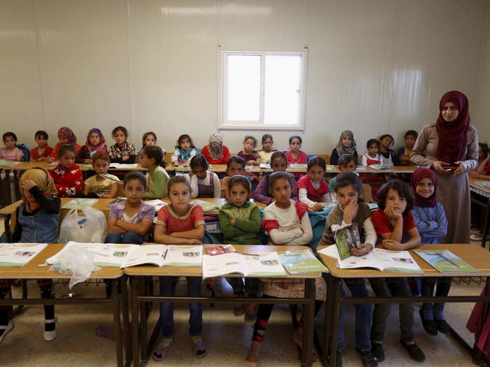 Hanan Anzi poses with Syrian refugee students inside their classroom at one of the UNICEF schools at the Al Zaatari refugee camp. It