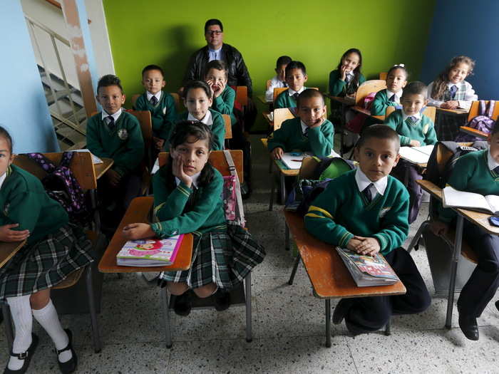 Father Juan Humberto Cruz poses for pictures with 4th-grade students at Semillas de Esperanza school in Soacha, near Bogota, Colombia.