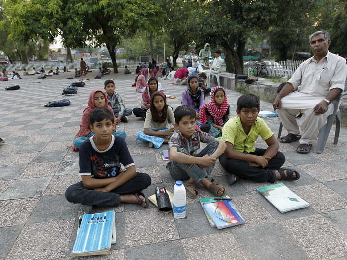 Master Mohammad Ayoub poses with his fifth-grade students at a local park in Islamabad. Ayoub, a Pakistani civil servant, started a program to educate underprivileged children in 1985. He provides the educational supplies from his personal income, and he and his volunteers teach the children English, Urdu and math. Their classroom is a local park during fair weather and a room in the local slum during the rainy season.