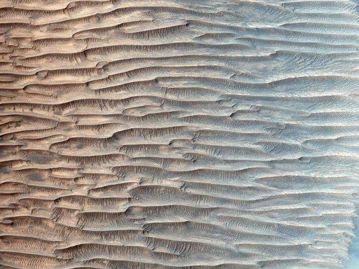 Take a close look at this unusual valley on Mars: You can see large horizontal ridges lining the valley floor with tiny, vertical sand dunes striping the face of each ridge. This suggests that the wind is either flowing from left to right (or visa versa).