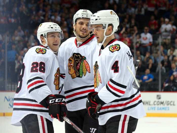 Artem Anisimov (15) celebrates with Niklas Hjalmarsson (4) and Ryan Garbutt (28) after scoring the first regular season goal, a short-handed goal, at the Barclays Center. The Blackhawks took a 1-0 lead.